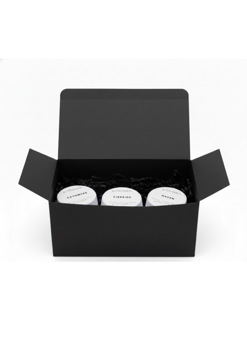 Open black gift box containing three white 2 oz candles in tins labelled Cashmere, Fireside and Haven on a white background.