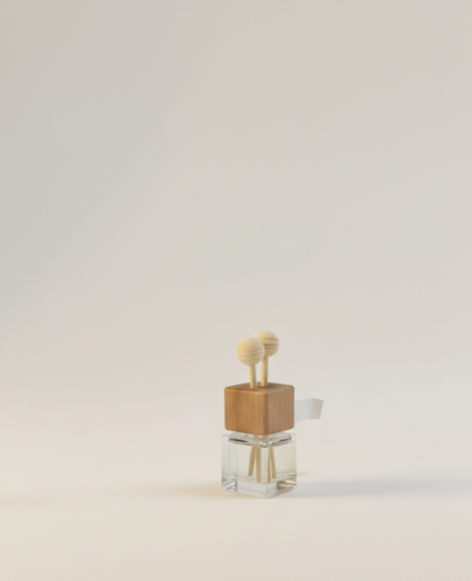 Small clear glass diffuser bottle with a wooden cap and vents topped with two round beads, set against a light beige background.