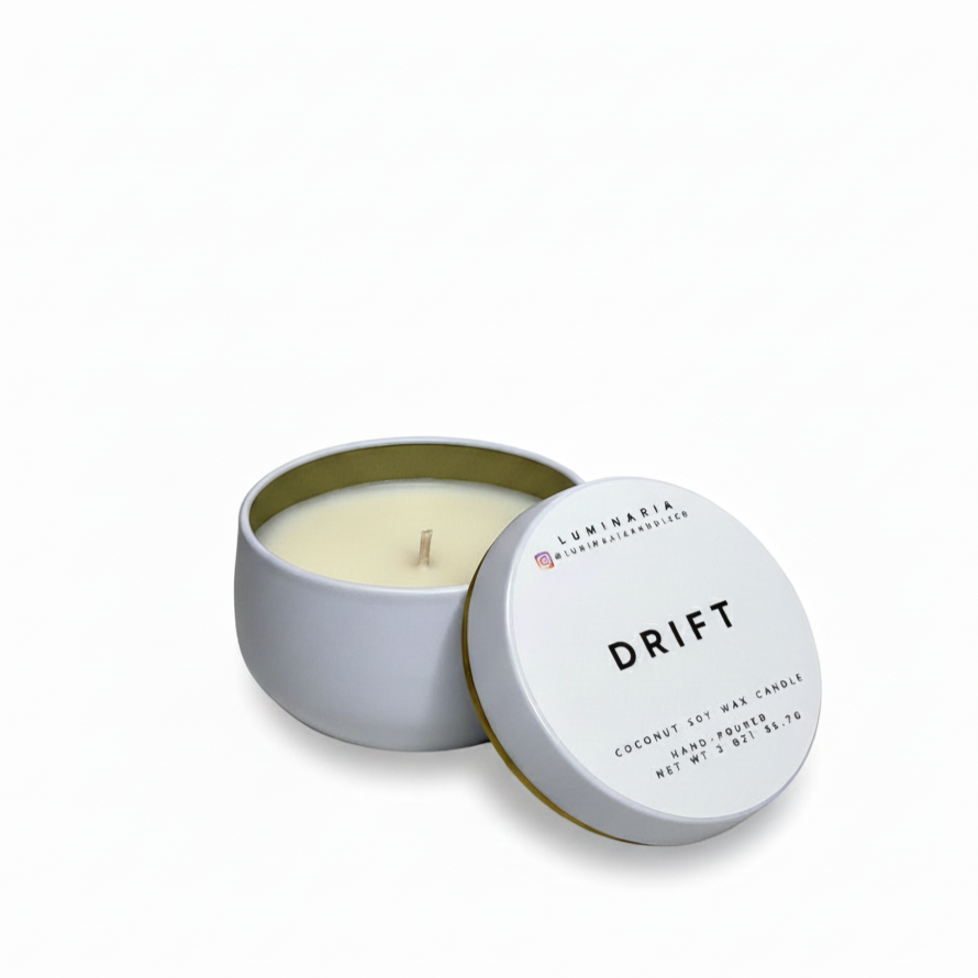 Open white metal tin candle with lid labeled 'Drift' placed on a white background