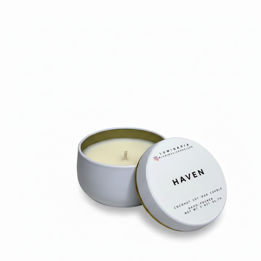 Open white metal tin candle with lid labeled 'Haven' placed on a white background